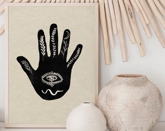 Könnte beinhalten: Ein gerahmter Schwarz-Weiß-Druck mit einer stilisierten Hand mit Augen-, Mond- und Blattdetails. Das Kunstwerk wird mit zwei Keramikvasen und einem dekorativen Sonnenstrahlspiegel aus Holz ausgestellt.