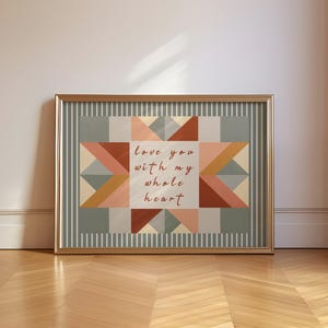May include: A framed rectangular wall art piece featuring a geometric star pattern in muted tones of sage green, terracotta, and cream. The centre white square displays the text "Love you with my whole heart" in a brown cursive script font.