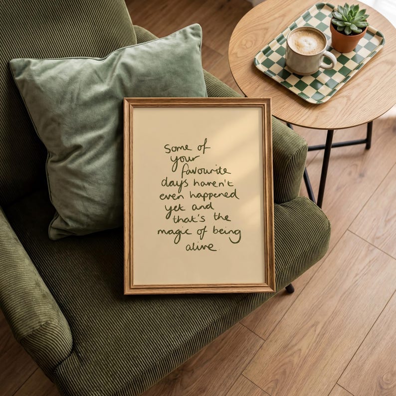 Minimalist typography print featuring the quote "Some of your favourite days haven't even happened yet and that's the magic of being alive" in an organic handwritten script. Warm beige background with olive green lettering creates a calming, hopeful and uplifting piece of inspirational wall art with a simple modern aesthetic.