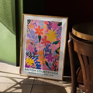 May include: A framed poster with a pink background and a colorful floral pattern. The poster has the text "British Countryside Blossoms Whisper Rural Tales".
