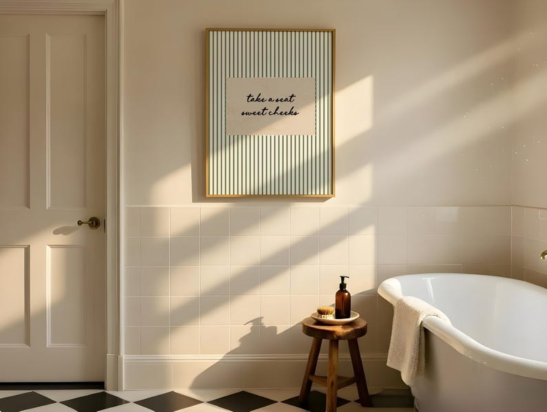 Funny bathroom wall art featuring olive green vertical pinstripes with a distressed cream scalloped label reading “take a seat sweet cheeks” in black handwritten script. Minimal vintage heritage inspired bathroom print with playful typography and a cosy boutique hotel aesthetic for guest bathrooms or powder rooms.