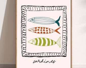 May include: A framed art print featuring three stylized fish in teal, orange, and green, set against a light pink background. The fish are within a black, hand-drawn frame, with the word "sardines" in a handwritten font below.