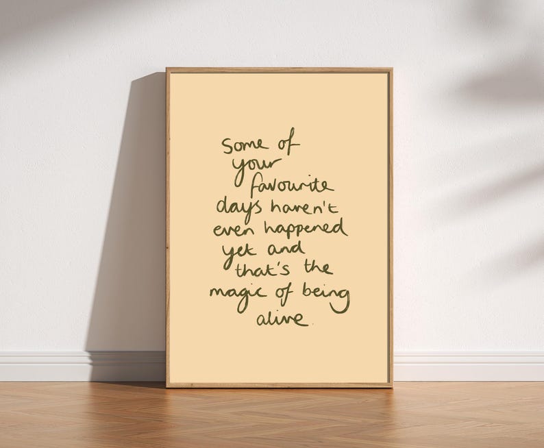 Minimalist typography print featuring the quote "Some of your favourite days haven't even happened yet and that's the magic of being alive" in an organic handwritten script. Warm beige background with olive green lettering creates a calming, hopeful and uplifting piece of inspirational wall art with a simple modern aesthetic.