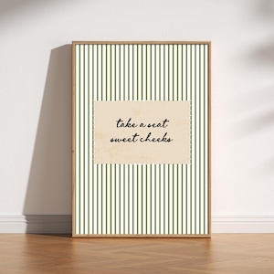 Funny bathroom wall art featuring olive green vertical pinstripes with a distressed cream scalloped label reading “take a seat sweet cheeks” in black handwritten script. Minimal vintage heritage inspired bathroom print with playful typography and a cosy boutique hotel aesthetic for guest bathrooms or powder rooms.