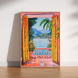 Puede incluir: Pintura enmarcada que representa una puerta abierta con contraventanas amarillas que dan a un lago y montañas. La obra de arte utiliza colores brillantes, incluyendo rosa, naranja y azul, creando una escena soleada. Se ve un balcón con una barandilla roja.