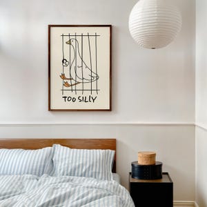 Bring a smile to your space with this Too Silly goose art print! A funny, minimalist illustration featuring a cheeky goose behind bars for being “too silly.” Perfect for adding personality to your home, office, or gallery wall.
This quirky silly goose animal print makes a wonderful gift for friends who love humor, cottagecore whimsy, or modern minimalist art. Designed to brighten up any corner and spark joy daily.