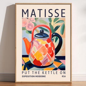 Könnte beinhalten: Ein farbenfrohes Poster mit dem Text "MATISSE" in Blau oben. Das Poster zeigt eine stilisierte Illustration einer roten und orangen Teekanne mit blauem Henkel und Deckel. Die Teekanne ist mit einem geometrischen Muster aus Rosa, Gelb und Grün verziert. Der Text "PUT THE KETTLE ON" steht in Schwarz unten auf dem Poster, darunter die Worte "EXPOSITION MODERNE" und "016".