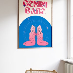Peut inclure: Une affiche de style r&eacute;tro avec le texte "GEMINI BABE" en lettres roses et bleues. L'affiche pr&eacute;sente une illustration rose du signe du zodiaque G&eacute;meaux sur un fond bleu avec des &eacute;toiles blanches.