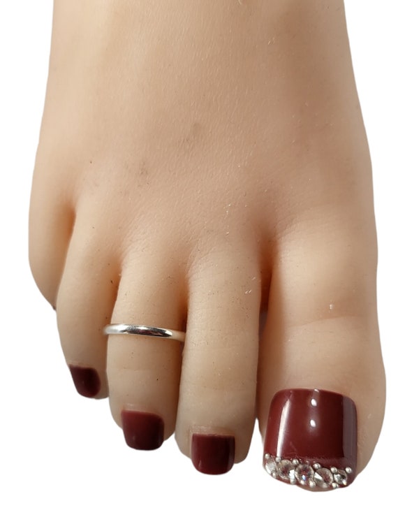Image of Lady Foot Finger Rings In Silver Metal Displayed At Dark Surface,  Female Lifestyle Product Concept Image-XJ049159-Picxy