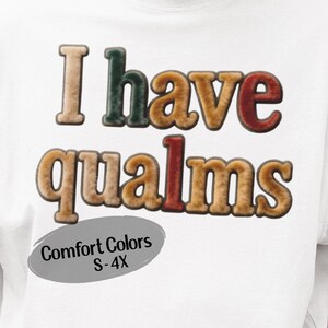 May include: White t-shirt with the phrase "I have qualms" in a textured, multi-colored font. The text is in shades of brown, green, and red. A gray oval below the text reads "Comfort Colors S-4X".