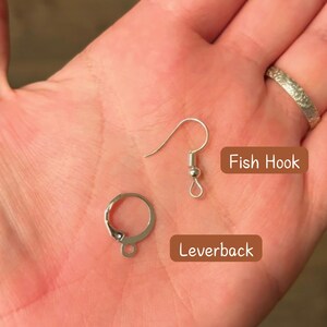 Pode incluir: Dois fechos para brincos, um &eacute; um gancho de peixe prateado e o outro &eacute; um fecho de alavanca prateado.