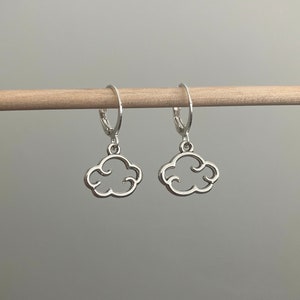 May include: A pair of silver hoop earrings with a cloud-shaped charm hanging from each hoop.