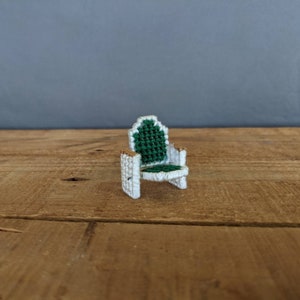 May include: A miniature white chair with a green fabric seat and back. The chair is made of yarn and is a small, decorative item.