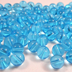 Puede incluir: Una gran cantidad de cuentas de vidrio azul claro. Las cuentas son redondas y tienen un acabado liso y brillante.