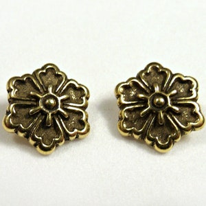 May include: A pair of gold-tone flower-shaped earrings with a raised center detail.