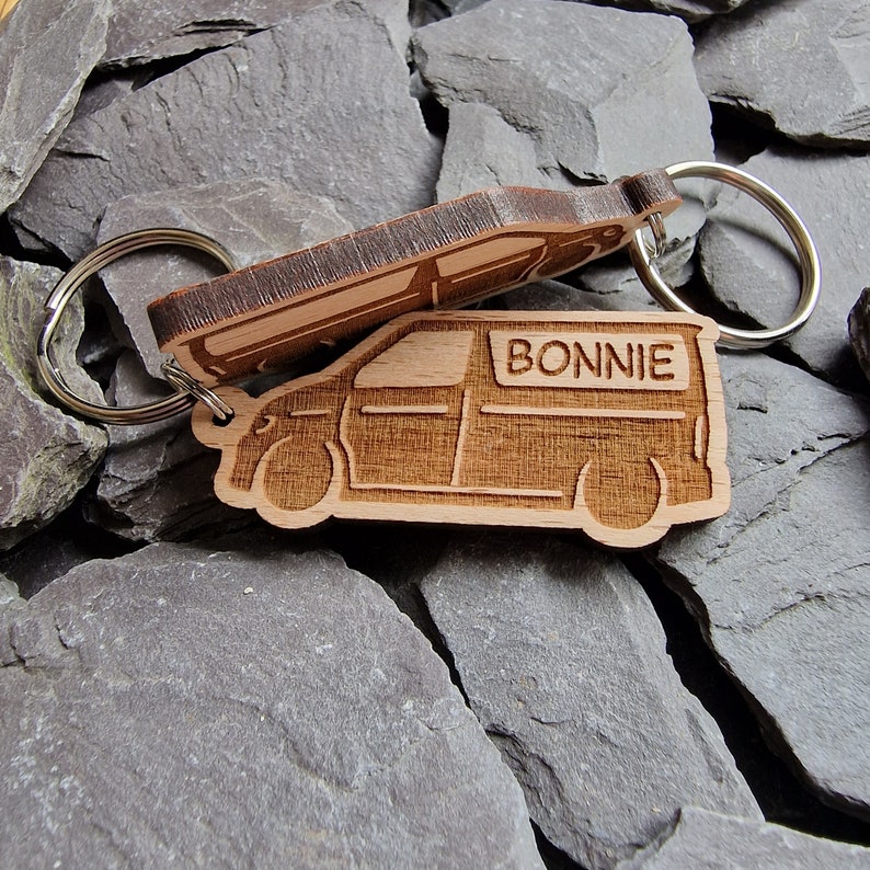 May include: Wooden keychain shaped like a van with the name "BONNIE" engraved on the side. The keychain is attached to a silver metal ring.