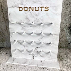 Donut Wall Stojak na pączki Donut Wall różne rozmiary. Biały wodoodporny plastik. Wolnostojący stojak ekspozycyjny marmurowy z nadrukowanym złotym tekstem