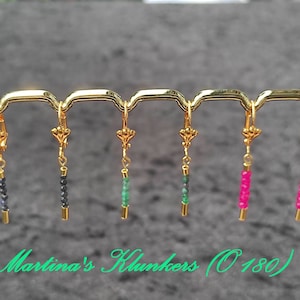 Könnte beinhalten: Sechs Paar goldene Ohrringe mit verschiedenen farbigen Perlen. Die Perlen sind schwarz, grün und rosa.