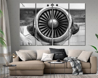 May include: A black and white photo of a jet engine. The engine is large and powerful, with a complex design of blades and a central hub. The photo is taken from a close-up perspective, showing the intricate details of the engine.