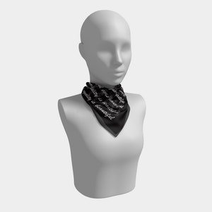 May include: Black square scarf with the text "Equality is beautiful" in white script. The scarf is displayed on a mannequin. The scarf is made of a silky material.
