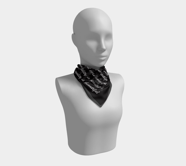 May include: Black square scarf with the text "Equality is beautiful" in white script. The scarf is displayed on a mannequin. The scarf is made of a silky material.