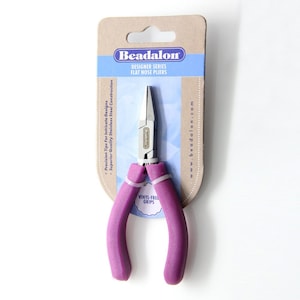 Könnte beinhalten: Flachzange mit violetten Griffen und vinylfreien Griffen. Die Verpackung trägt die Aufschrift "Beadalon Designer Series Flat Nose Pliers" und "www.beadalon.com".