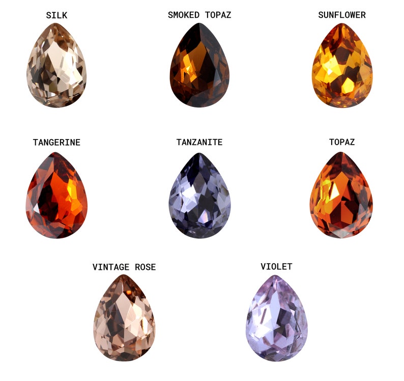 May include: Nine teardrop-shaped glass beads in various colors, including tan, orange, brown, purple, and blue. The beads are arranged in three rows of three, with each bead labeled with a color name.