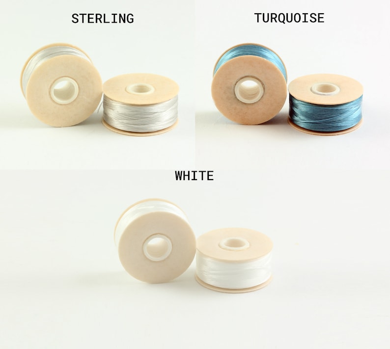 May include: Three spools of thread in different colors: sterling, turquoise, and white. Each spool is made of wood and has a hole in the center for threading.