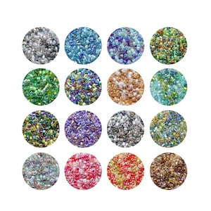 Può includere: Sedici disposizioni circolari di piccole perline colorate. Le perline sono in vari colori, tra cui argento, blu, verde, viola, oro e rosso. Le perline sono probabilmente per la creazione di gioielli o altri progetti artigianali.