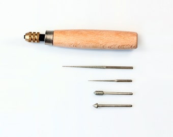 May include: A set of four diamond tipped tools for jewelry making. The tools are attached to a wooden handle with a metal chuck. The tools are used for shaping, polishing, and engraving jewelry.