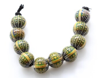 May include: A strand of yellow, green, and black patterned beads. The beads are round and have a textured surface.