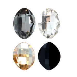 May include: Four oval-shaped crystal beads in different colours: clear, black, grey, and gold.