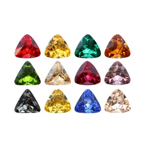 Può includere: Una collezione di dodici gemme triangolari in vari colori, tra cui rosso, giallo, verde e blu. Ogni gemma ha una superficie sfaccettata, che riflette la luce. Le gemme sono disposte su uno sfondo bianco.