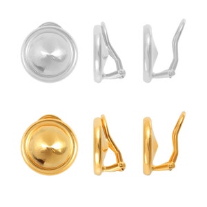 May include: A pair of silver and gold clip-on earrings. The earrings are round with a raised center and a smooth finish. The silver earrings have a polished finish, while the gold earrings have a brushed finish.