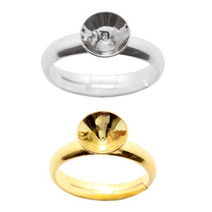 May include: Two ring blanks, one silver and one gold, with a round bezel setting. The bezels are designed to hold a cabochon stone.