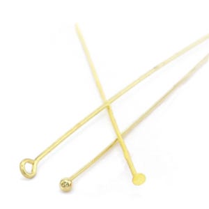 Puede incluir: Tres alfileres de cabeza dorada con diferentes estilos de cabeza: un bucle, una bola y un disco plano.