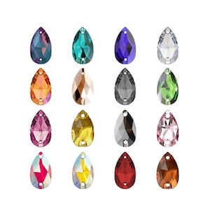 Puede incluir: Una colección de dieciséis cristales facetados en forma de lágrima dispuestos en una cuadrícula de cuatro por cuatro. Cada cristal presenta dos pequeños orificios para coser o sujetar y muestra un color único, incluyendo morado, turquesa, azul, transparente, naranja, beige, gris, verde, rosa, amarillo, negro, rosa claro, iridiscente, multicolor, rojo y marrón.