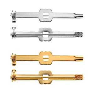 Może przedstawiać: Cztery metalowe zapięcia do broszki, dwa srebrne i dwa złote, z kwadratowym otworem w środku. Zapięcia są zaprojektowane do mocowania z tyłu broszki.