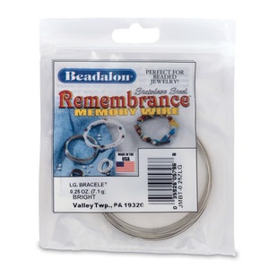 May include: A package of silver-colored stainless steel memory wire for jewelry making. The package is labeled "Beadalon Remembrance Memory Wire" and includes the text "LG. BRACELET 0.25 OZ. (7.1 g) BRIGHT Valley Twp., PA 19320".