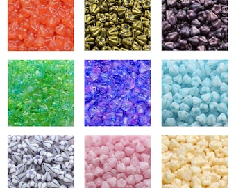 Op de afbeelding: Assortiment van glazen kralen in verschillende kleuren en vormen. De kralen zijn klein en hebben een bloemvormig ontwerp. De kleuren omvatten oranje, goud, paars, groen, blauw, roze en wit.