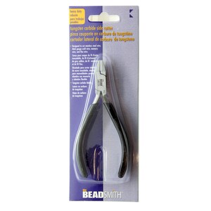 May include: A package containing a tungsten carbide side cutter. The tool has black handles and silver cutting edges. The packaging is purple and white, with text in English and Spanish.