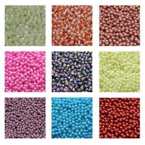 May include: Assortment of colourful round beads in various colours, including white, pink, light blue, purple, red, and orange. The beads are arranged in a grid pattern.