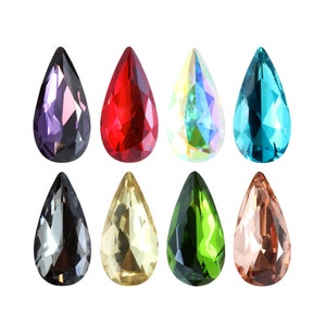 May include: Assortment of ten teardrop-shaped glass rhinestones in various colors, including purple, red, clear, blue, black, yellow, green, and pink.