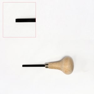 Könnte beinhalten: Ein Werkzeug mit Holzgriff und schwarzer Klinge. Das Werkzeug wird zum Schnitzen und Formen von Metall verwendet.