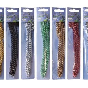 May include: Seven spools of aluminum chain in various colors, including gold, black, silver, green, red, and a lighter silver. Each spool is labeled "Aluminum Chain 36" and "Bead Smith".