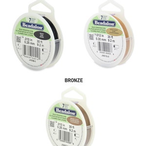 May include: A spool of 7-strand Beadalon bead stringing wire in black, gold, and bronze. The wire is 0.010 inches thick and 30 feet long. The spool is labeled with the Beadalon brand name and the wire's thickness and length.
