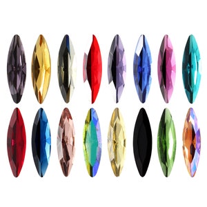 Könnte beinhalten: Sortiment von 15 Marquise-förmigen Strasssteinen in verschiedenen Farben, darunter Rot, Blau, Grün, Gold und Schwarz.