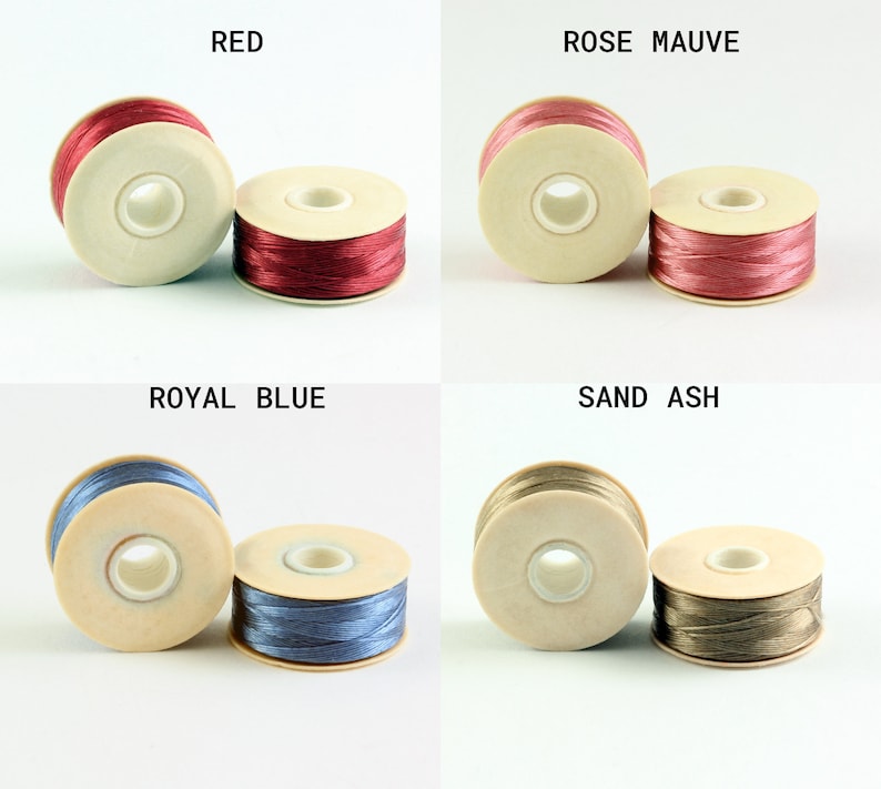 May include: Four spools of thread in different colors: red, rose mauve, royal blue, and sand ash. Each spool is wound with thread and has a white plastic bobbin.