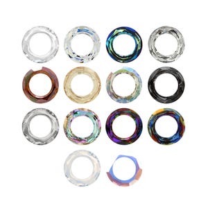 Op de afbeelding: Een collectie van veertien ronde kristallen kralen gerangschikt in vier rijen. De kralen hebben verschillende afwerkingen, waaronder heldere, iriserende, metallic, zwarte, bruine en meerkleurige tinten. Elke kraal heeft een gefacetteerd oppervlak.