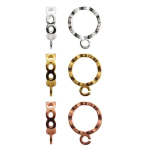 Puede incluir: Tres cierres de metal plateado, dorado y oro rosa para la elaboración de joyas. Cada cierre tiene un anillo redondo con un borde texturizado y un pequeño bucle en la parte inferior.